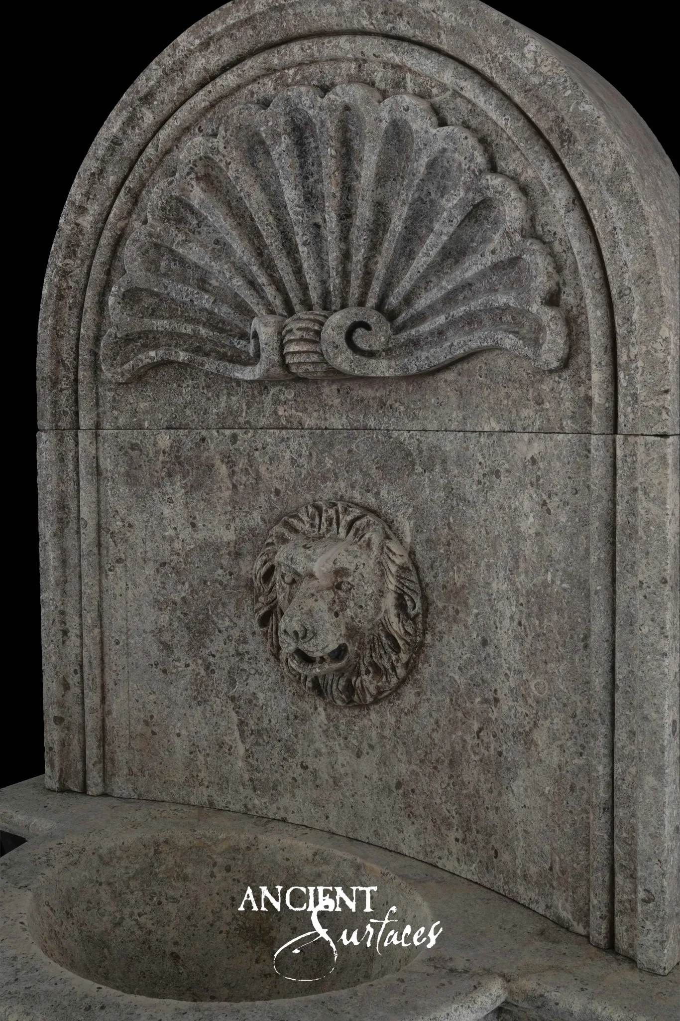 Reclaimed antique limestone wall fountain from Ancient Surfaces with a carved scallop shell crest and lion mask spout above an oval basin