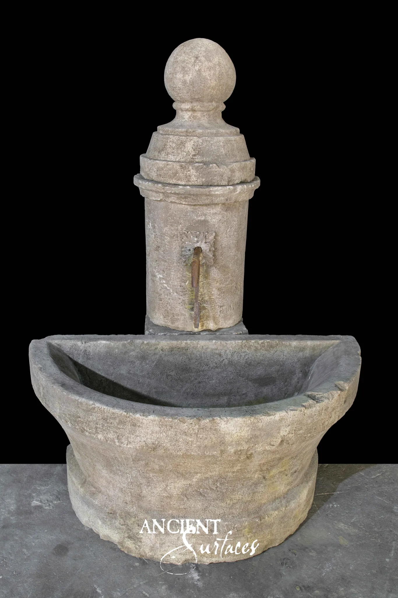 Reclaimed antique limestone pillar wall fountain from Ancient Surfaces with a ball finial, iron spout and half round carved basin