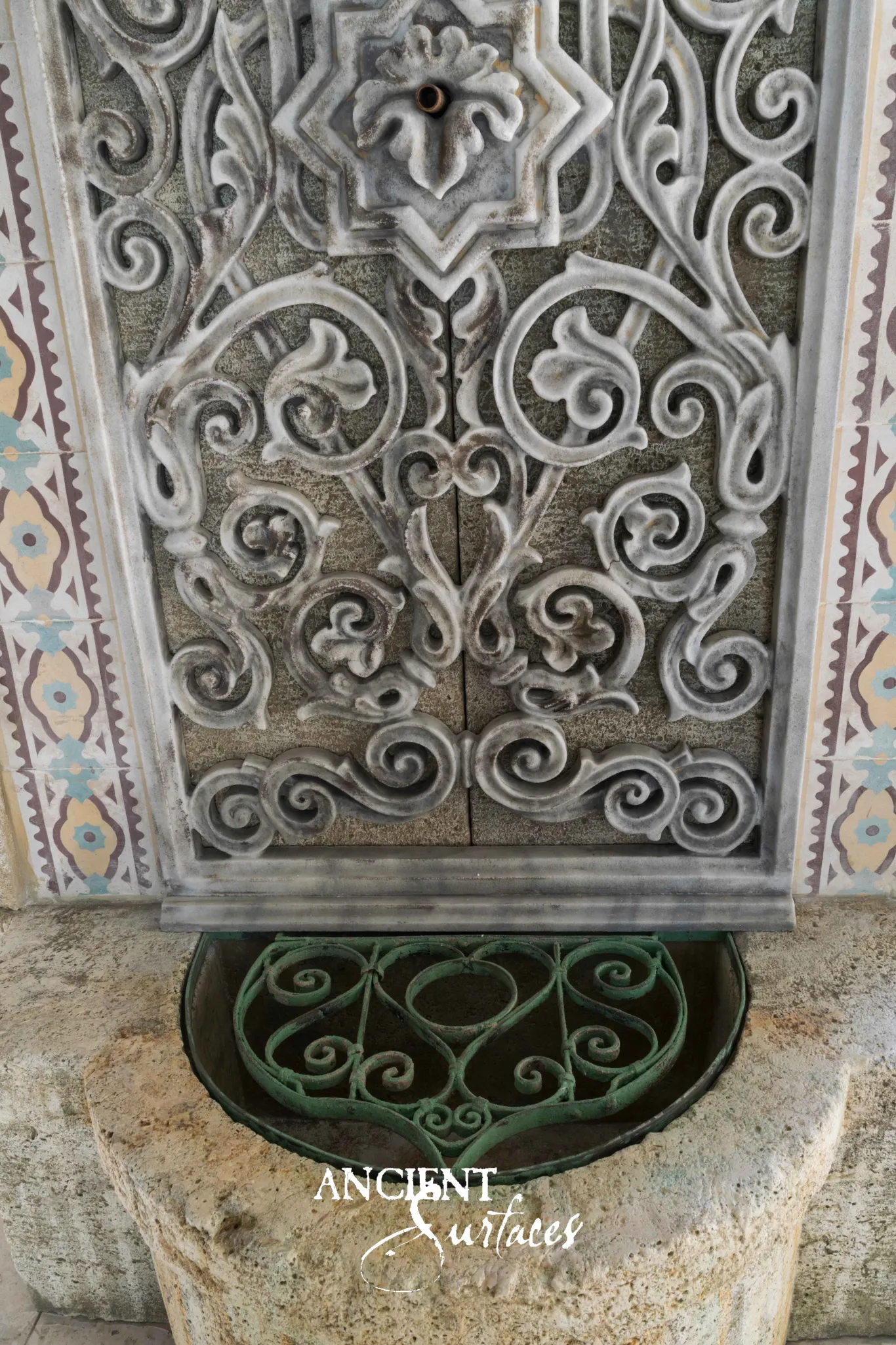 Reclaimed antique limestone fountain panel from Ancient Surfaces carved in openwork arabesque around a star medallion between painted tile borders
