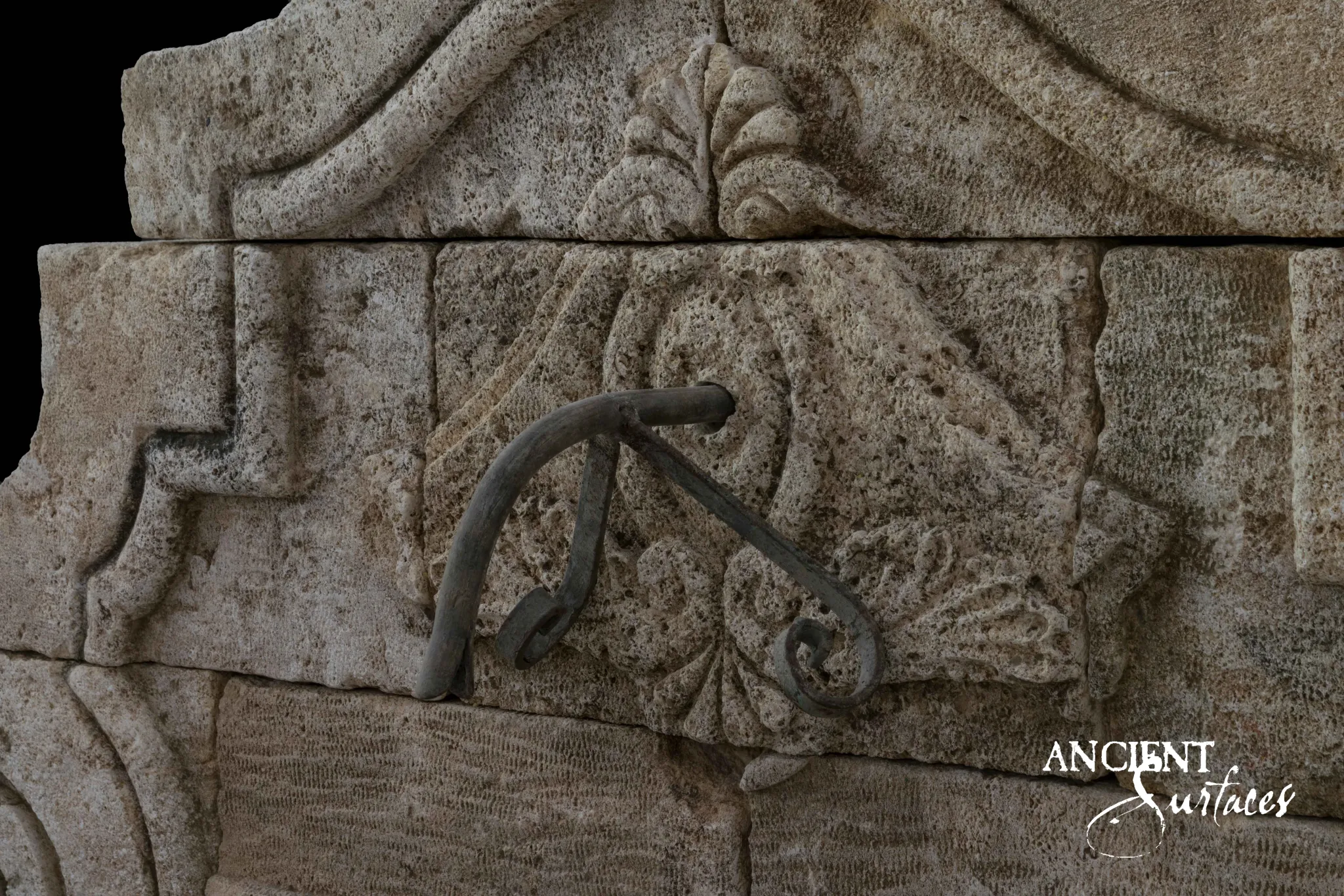 Carved acanthus and drapery detail on an Ancient Surfaces reclaimed limestone wall fountain with a forged iron spout